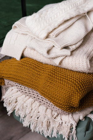 Stack of women's dresses with knitted wool sweaters or plaids. Various knitting patterns, stacked....