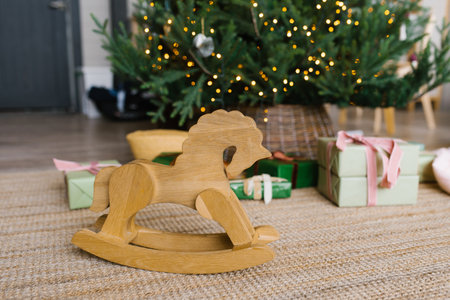 Wooden horse toy wheelchair on the background of Christmas tree lights and gifts with copy spaceの写真素材