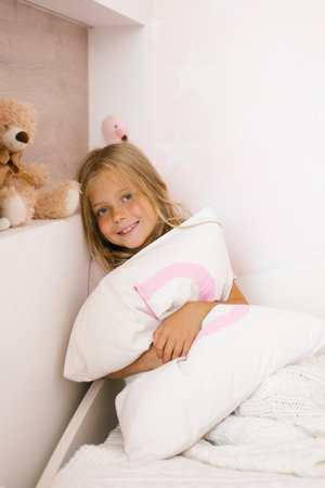 Beautiful girl hugs a pillow on the bed in the nurseryの写真素材