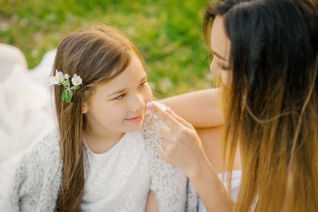 Mom has fun with her daughter outdoors. Mom touches the tip of her baby's noseの写真素材