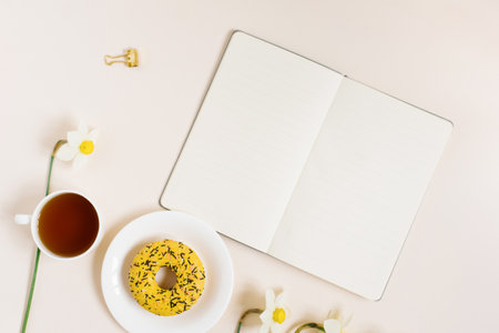 Flat lay lady blogger or freelancer workspace with flowers, notebook, office supplies on a beige background. copy spaceの写真素材