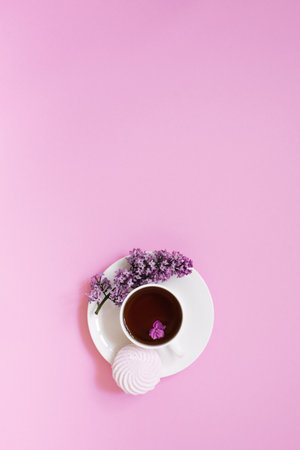 Flower arrangements of beautiful purple lilac on a pink background with a cup of tea. Women's office desk, stylish stock image, Flat layout, top view with Empty copy spaceの写真素材