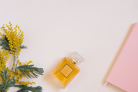 Fashionable women's flat lay with a clean notebook, a bouquet of yellow mimosa flowers and perfume on a beige table. planning concept.の写真素材