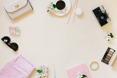 Flat lay fashion blogger women. Bag, clothes, camera, cup of tea, cosmetics on beige background with copy spaceの写真素材