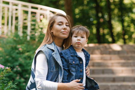 Mother with a three-year-old child playing outdoors on a sunny day in a city parkの写真素材
