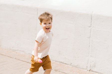 Blur cute Caucasian boy of three emotionally runs through the park in the summerの写真素材