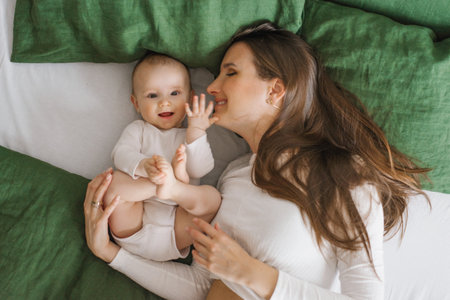 Happy smiling mother and child lying on the bed at home on the bed, top viewの写真素材