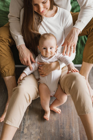 Portrait of a six-month-old baby boy who is hugged by his parents' handsの写真素材