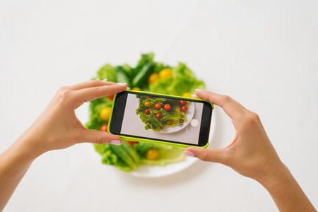 Top view of a woman's talking hands photo of fresh healthy food before eating it with a smartphoneの写真素材