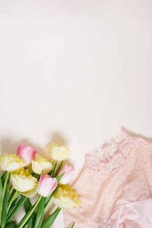 Women's clothing and a bouquet of spring bright tulip flowers on a beige background with a copy space. Flat lay concept of women's fashion, mother's day, birthday and springの写真素材