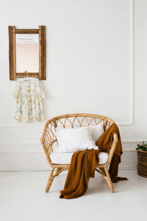 A wicker armchair with a brown plaid in a white room in Scandinavian styleの写真素材