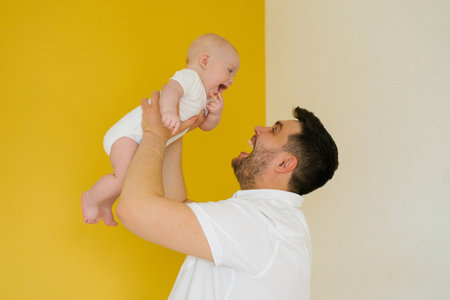 Positive cheerful dad holds his son in his arms. happy parent and baby