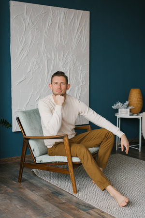 Young man sits lama in a cozy chair and looks at the camera