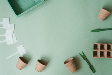 Planting a flower in a flower pot. A flat composition with garden tools and peat on a green background. copy spaceの写真素材
