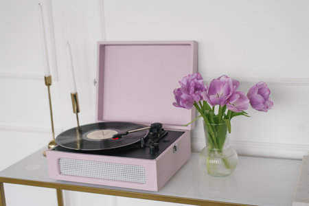 Beautiful lilac tulips in a glass vase, retro record player and candles in the living room