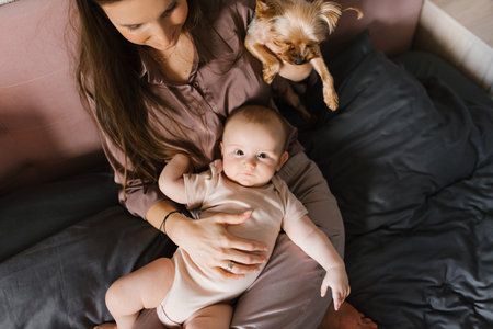 Happy family, mom, baby and dog playing on the bedの写真素材