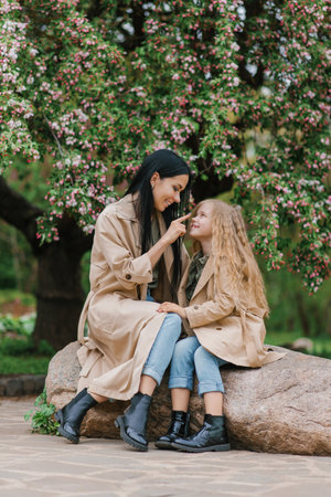 Mother and little daughter in a blooming spring garden. Mom loves her baby.. Happy family on a beautiful spring day, Mother's dayの写真素材