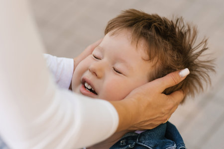 Mom holds the head of her naughty little harmful son in her handsの写真素材
