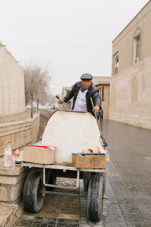 Bukhara, Uzbekistan. December 2022. Seller of hot samsa from tandoor on the street of the old townのeditorial素材