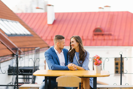 Attractive young couple in love sitting at the cafe table outdoorsの写真素材