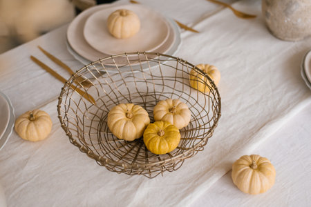 Small pumpkins in a wicker basket on the table for Thanksgivingの写真素材