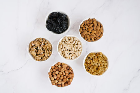Various nuts and dried fruits in white bowl on a marble background. top viewの写真素材