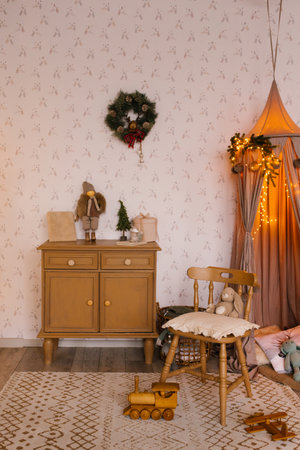 Interior of a children's room decorated for Christmas. A tent with toys and pillows, a Christmas tree, a wardrobe and a chair in beige tonesの写真素材