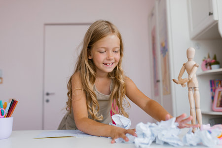 Caucasian schoolgirl having fun at recess or on vacation, playing with mint, crumpled paper made from school notebooksの写真素材
