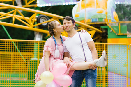 Young happy funny couple in love walks and has fun in an amusement parkの写真素材