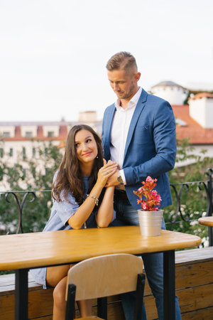 Stylish couple in love at a table in a street cafe communicates and flirts with each otherの写真素材