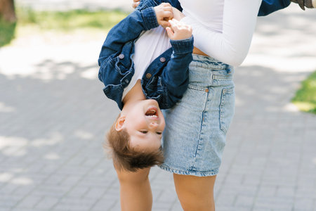 Happily laughing boy upside down on his hands and moms in a summer parkの写真素材