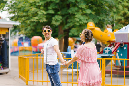 Delighted adult couple is having fun together in an outdoor amusement park during their leisure time. The concept of the lifestyle of young peopleの写真素材