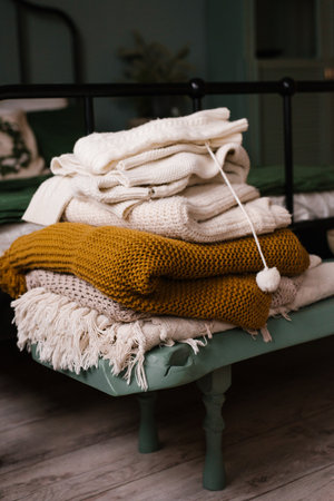 Stack of knitted blankets on the bedside table in the bedroom, decorated for Christmas and New Yearの写真素材