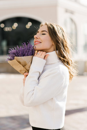 Sensual portrait of a young woman with a bouquet of purple flowersの写真素材