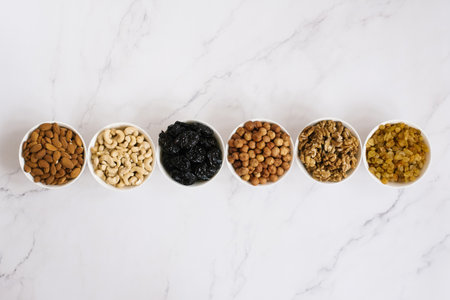 Various nuts and dried fruits in white bowl on a marble background. Top viewの写真素材