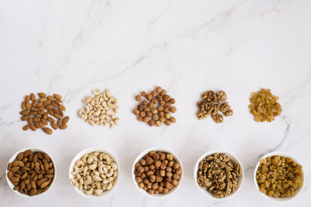 Various nuts and dried fruits in white bowls on a marble background. Top view, copy spaceの写真素材