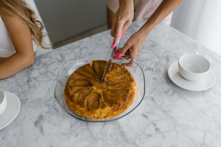 Close up of mother's hands cutting off a piece of blackberry pie for a child at the tableの写真素材