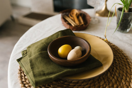 Table with a green napkin and a yellow bowl with easter eggs on it