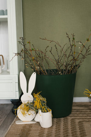 Green vase with a rabbit figurine and some flowers in it for Easter