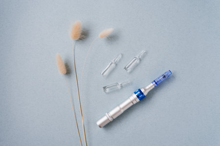 Fractional mesotherapy device and serum ampoules for skin on a blue background in the cosmetologist's officeの写真素材