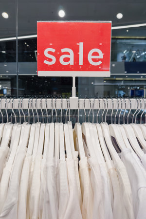 Rack of white clothes with a red sign that says Sale hanging from it