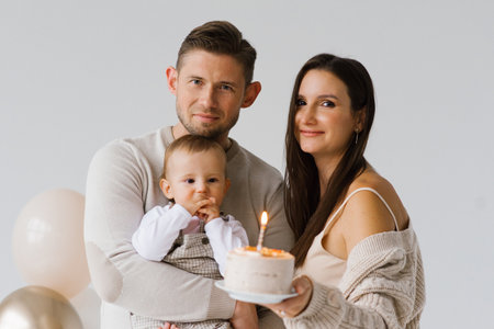 Happy parents mom and dad with their son celebrate birthday with cake and balloonsの写真素材