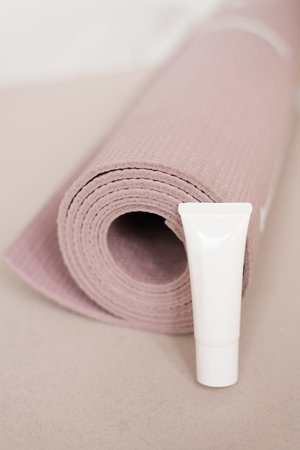 White tube of cream lies next to the yoga pink matsの写真素材