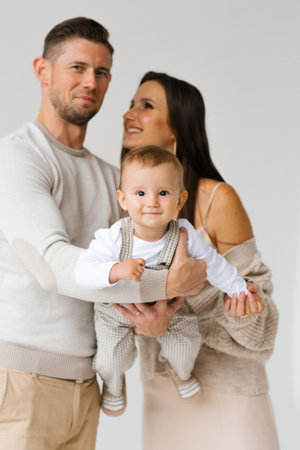 Happy family of three, a man, a woman and a baby, are hugging each otherの写真素材