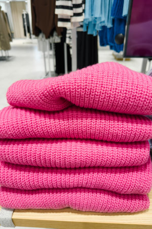 Pink knit sweaters stacked on top of each other in store