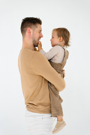 Young father holds a two year old son in brown clothes in his armsの写真素材