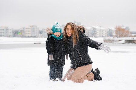 Happy woman and boy child are playing in the snowの写真素材
