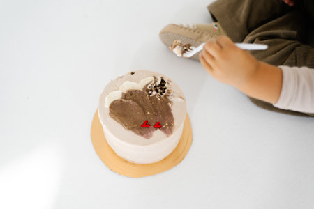 Child is eating a cake with a red heart on it. Hands top viewの写真素材
