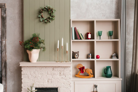 Beige fireplace mantel with christmas wreath and wooden rocking horse in living roomの写真素材