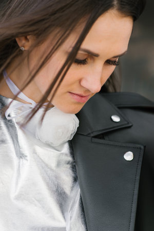 Young woman wearing a black leather jacket and a white shirt with a flower on itの写真素材